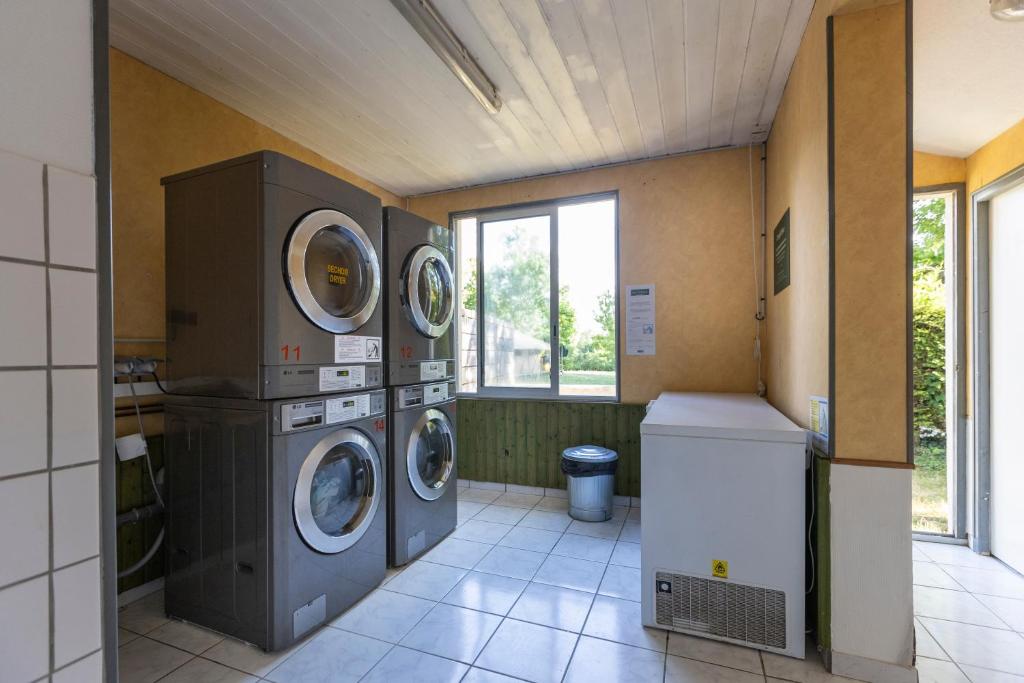 une buanderie avec 3 lave-linge et une fenêtre dans l'établissement Huttopia La Plage Blanche, à Ounans
