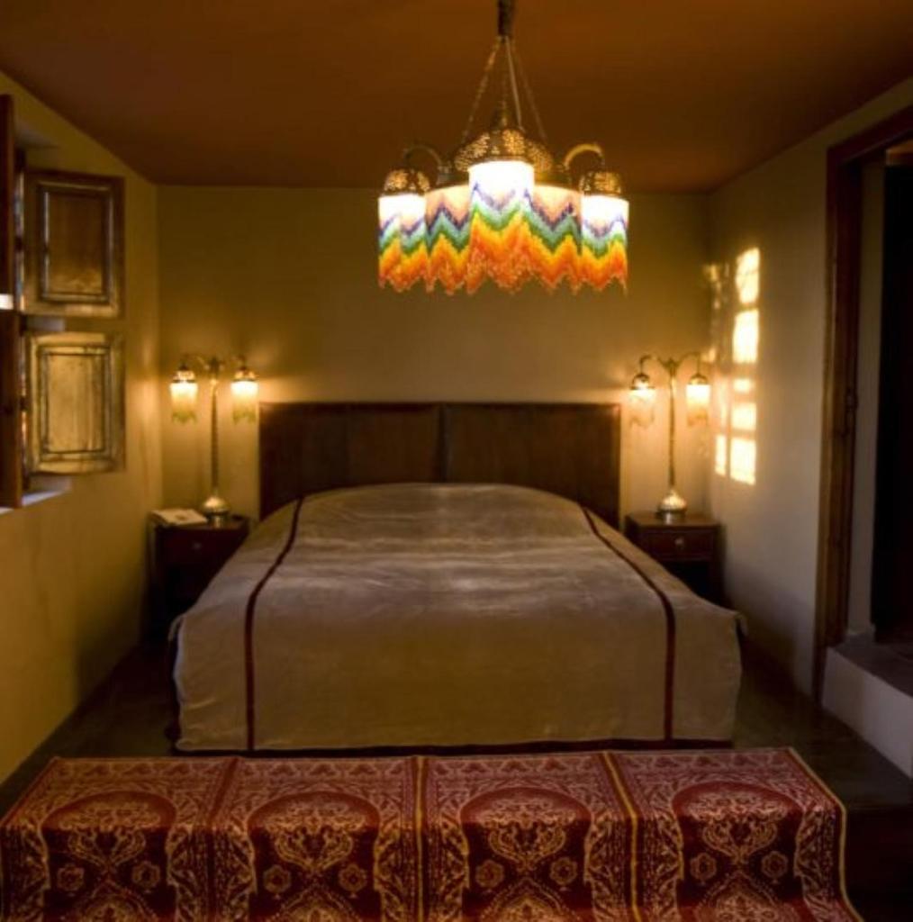 une chambre avec un lit et un lustre dans l'établissement Kssour Agafay Jemaa El Fna, à Marrakech