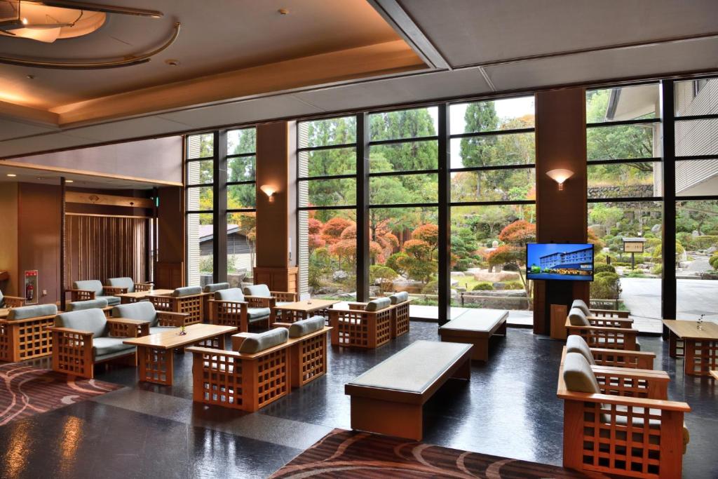 un restaurant avec des tables et des chaises et de grandes fenêtres dans l'établissement Yunogo Bishunkaku, à Mimasaka