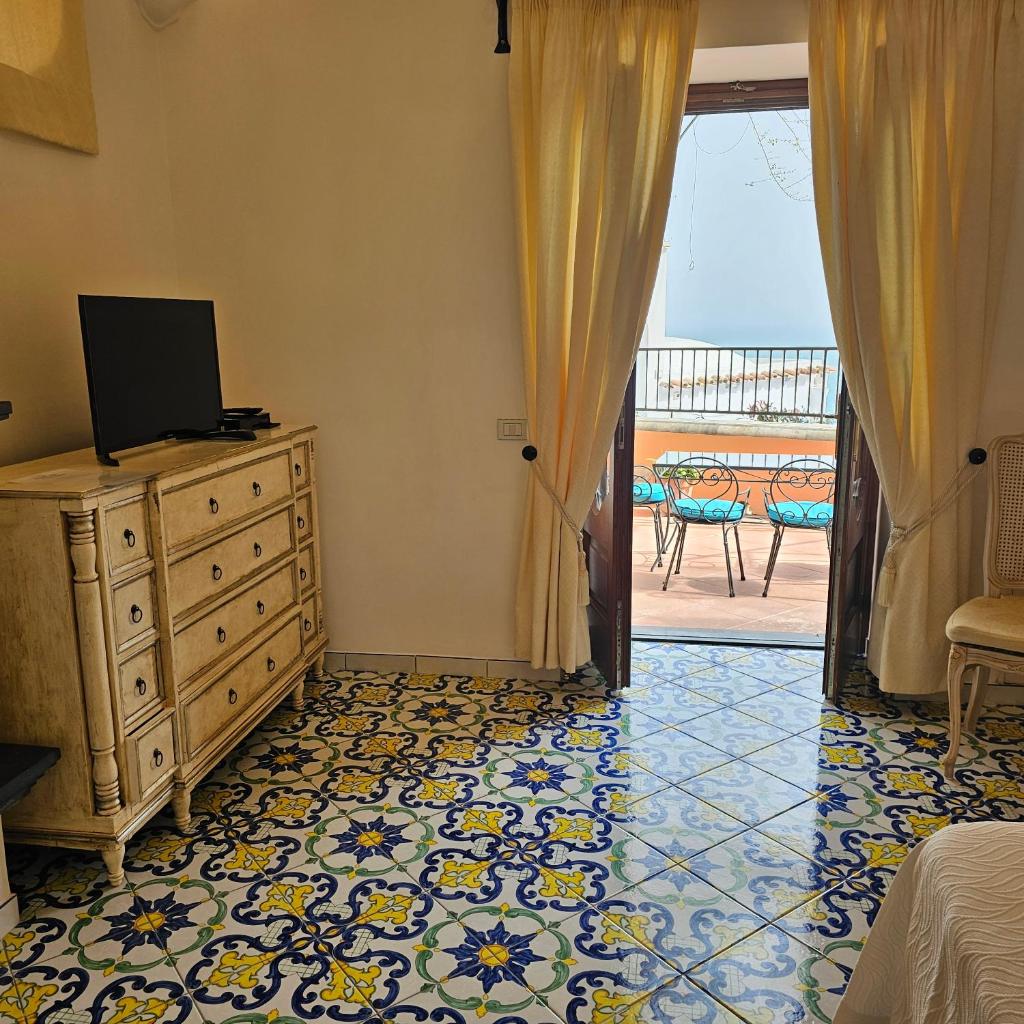 - une chambre avec une commode et une porte donnant sur une terrasse dans l'établissement Villa Principe Giovanni, à Positano
