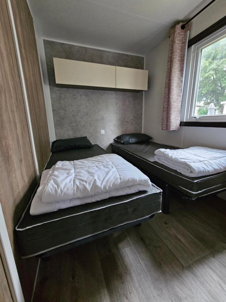 une chambre avec deux lits et une fenêtre dans l'établissement Jolie Mobil home 103, à Saint-Jean-de-Monts