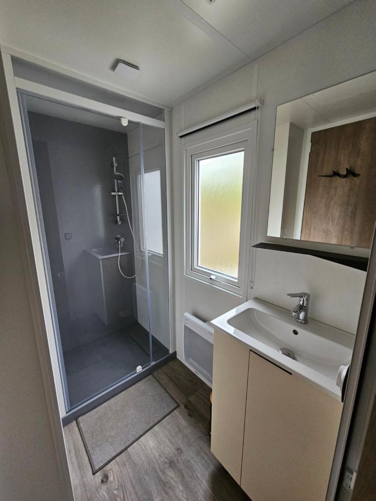 La salle de bains est pourvue d'un lavabo et d'une douche. dans l'établissement Jolie Mobil home 103, à Saint-Jean-de-Monts