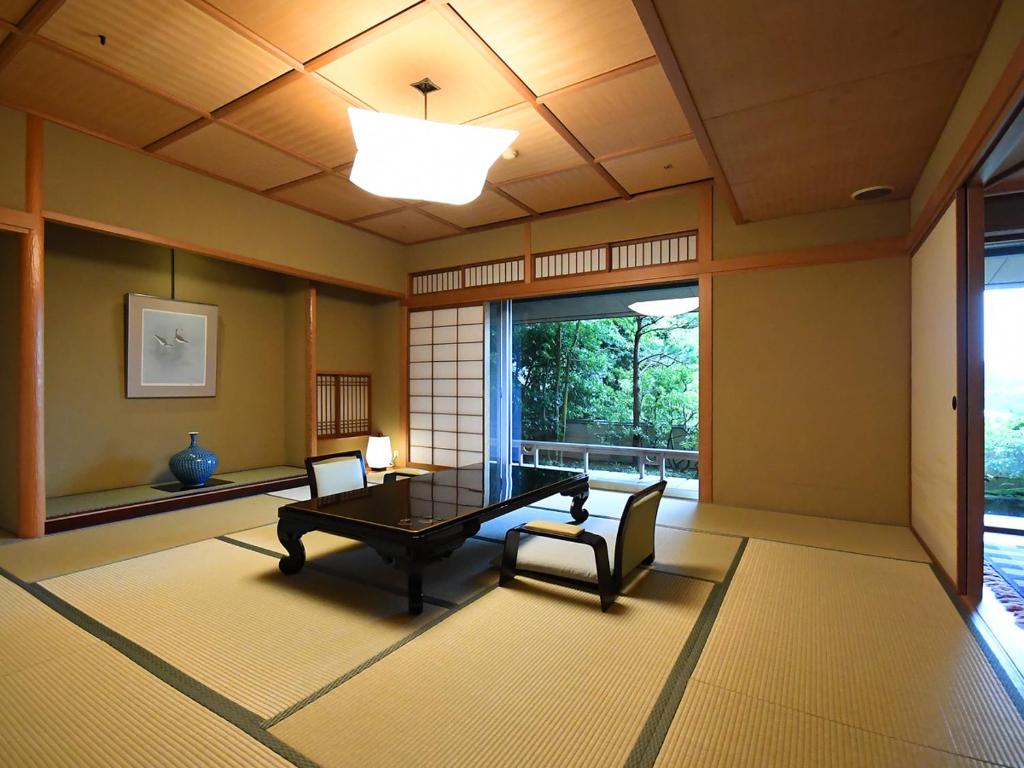 une salle à manger avec une table et des chaises et une fenêtre dans l'établissement Seizan Yamato, à Itō