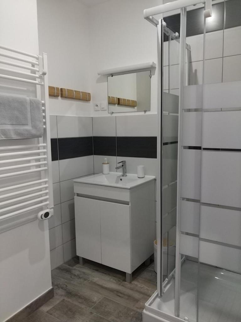 une salle de bain blanche avec un lavabo et un miroir dans l'établissement Les Balcons de L'Izoard, à Arvieux