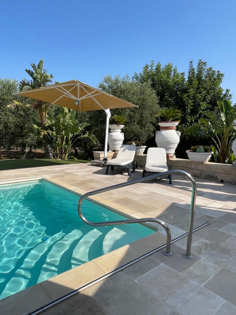 une piscine avec deux chaises et un parasol dans l'établissement Villa Forester - Puglia Mia Apartments, à Monopoli