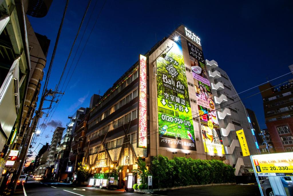 un grand bâtiment avec des panneaux de néon sur son côté dans l'établissement Hotel Balian Resort Kinshicho, à Tokyo