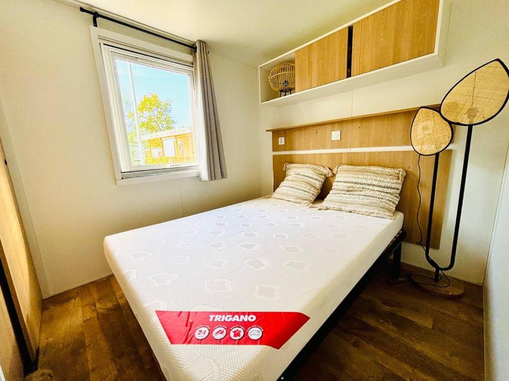 - une petite chambre avec un grand lit dans l'établissement Le Nid des Viviers - Bungalow au bord de l'eau, à Lège-Cap-Ferret