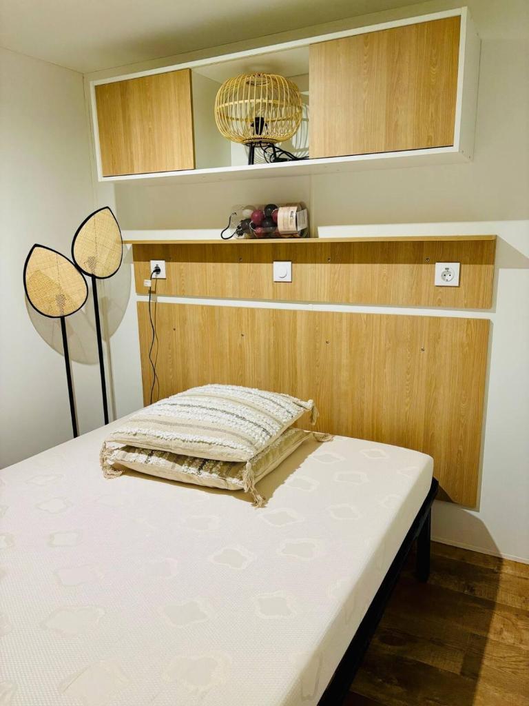 un lit dans une chambre avec un mur en bois dans l'établissement Le Nid des Viviers - Bungalow au bord de l'eau, à Lège-Cap-Ferret