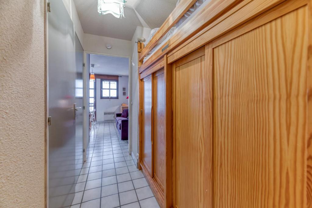 un couloir avec des armoires en bois et du carrelage dans l'établissement Granges 25 - Au Pied Des Pistes, à Villard-Reculas