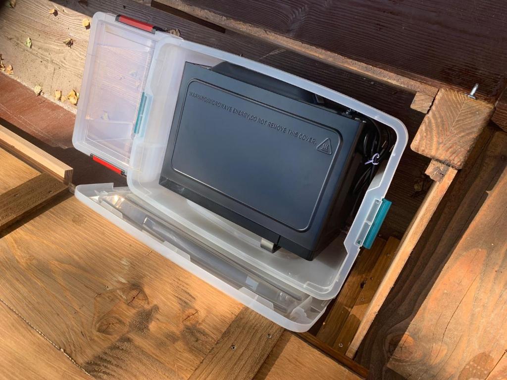 une petite télévision assise dans un récipient en plastique au sol dans l'établissement Village Toue du Domaine des Demoiselles, à Chassenard