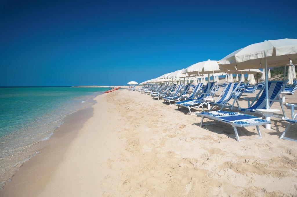 une rangée de chaises et de parasols sur une plage dans l'établissement Costa del Salento - CDSHotels, à Lido Marini