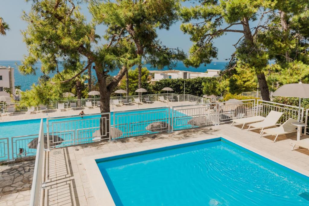 - une piscine avec des chaises, des arbres et l'océan dans l'établissement Grand Hotel Riviera - CDSHotels, à Santa Maria al Bagno
