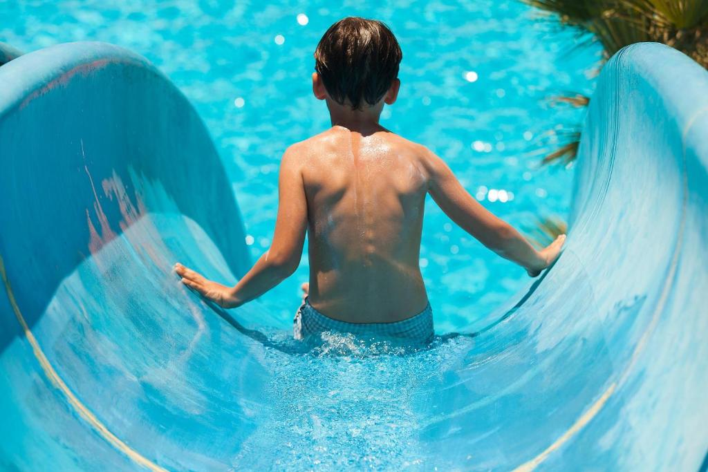 Un jeune garçon qui descend un toboggan dans l'eau dans l'établissement CDSHotels Terrasini - Città del Mare, à Terrasini