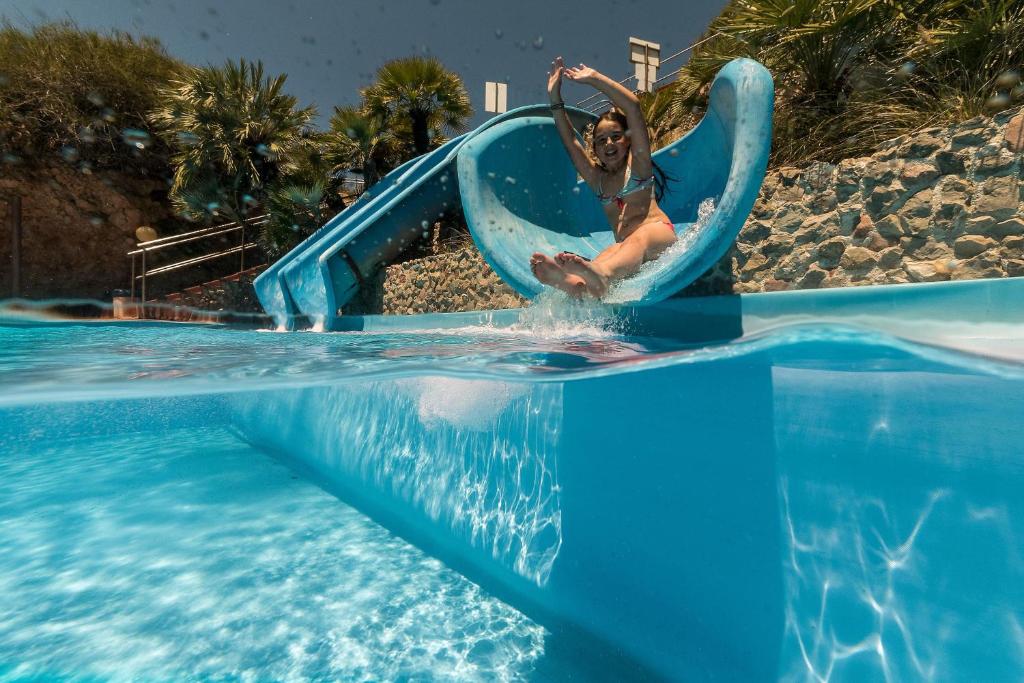 une femme descend un toboggan aquatique dans un complexe hôtelier dans l'établissement CDSHotels Terrasini - Città del Mare, à Terrasini