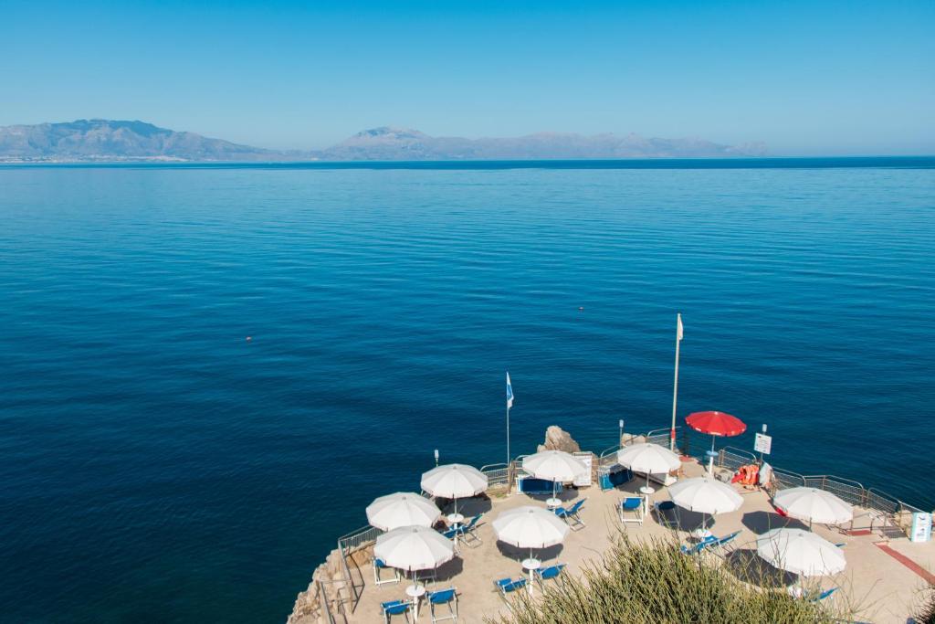 un groupe de parasols et de chaises sur un quai dans l'eau dans l'établissement CDSHotels Terrasini - Città del Mare, à Terrasini