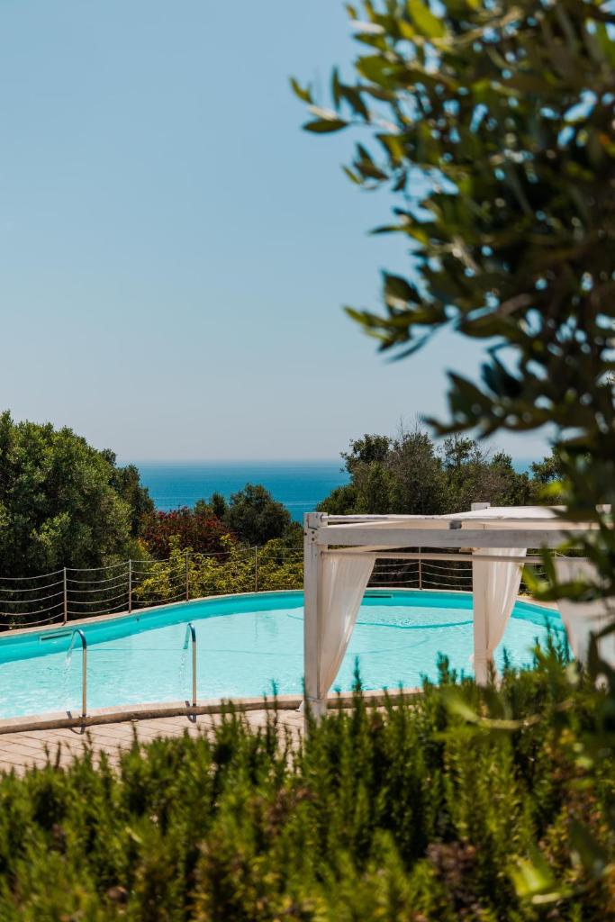 une piscine bleue avec un auvent blanc et l'océan dans l'établissement Marenea Suite Hotel - CDSHotels, à Marittima