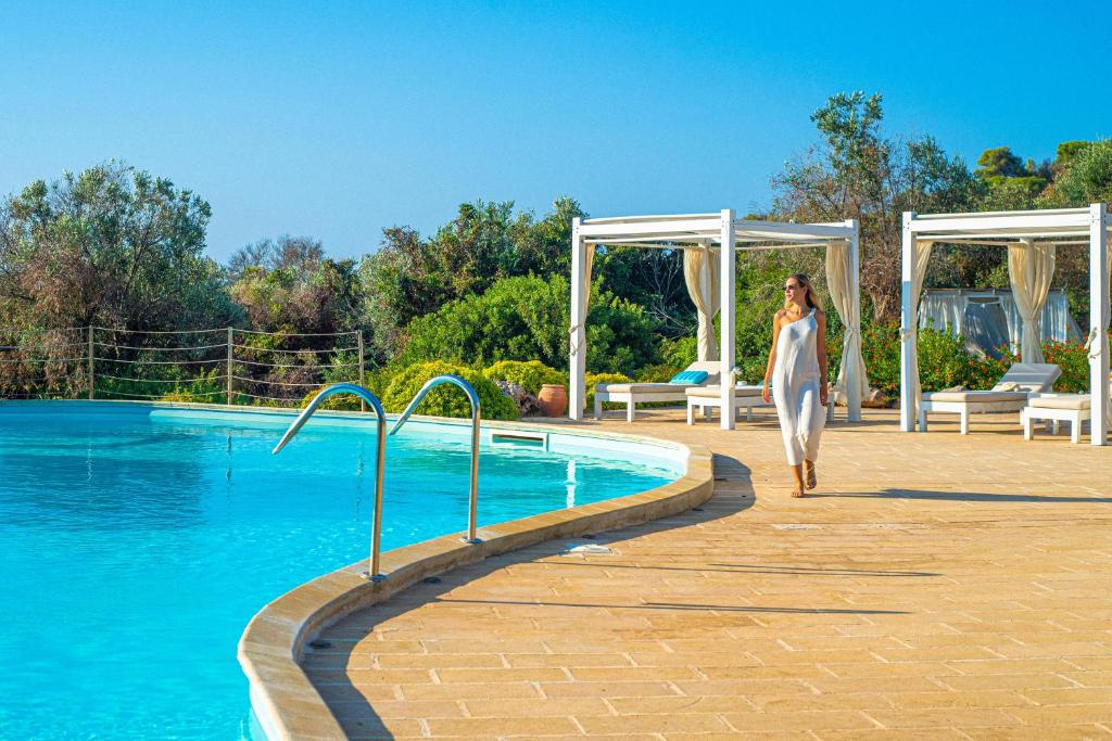 une femme s'engageant sur un chemin à côté d'une piscine dans l'établissement Marenea Suite Hotel - CDSHotels, à Marittima