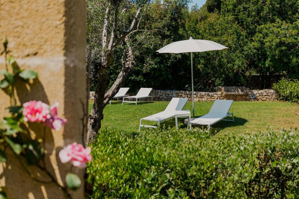 - une rangée de chaises et un parasol dans la cour dans l'établissement Marenea Suite Hotel - CDSHotels, à Marittima