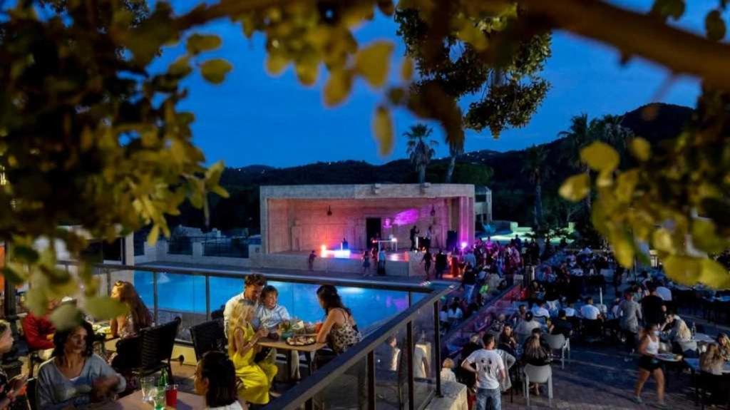 un groupe de personnes assises autour d'une piscine la nuit dans l'établissement Camping 5 étoiles - Parc aquatique - eebaff, au Muy 14 autres photos