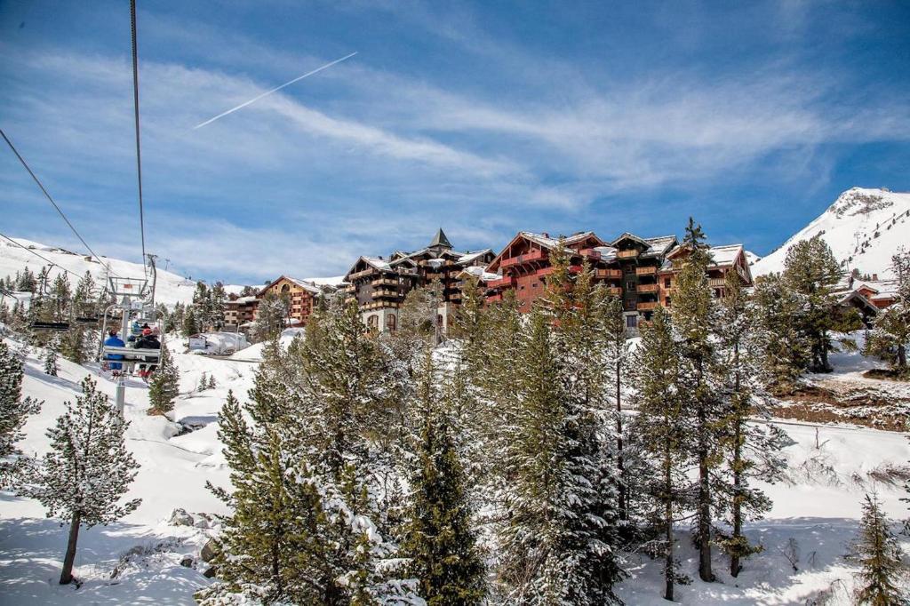 un lodge de ski dans la neige avec des arbres dans l'établissement Résidence & Spa Les Sources de Marie - Arc 1950 Le Village, à Arc 1950