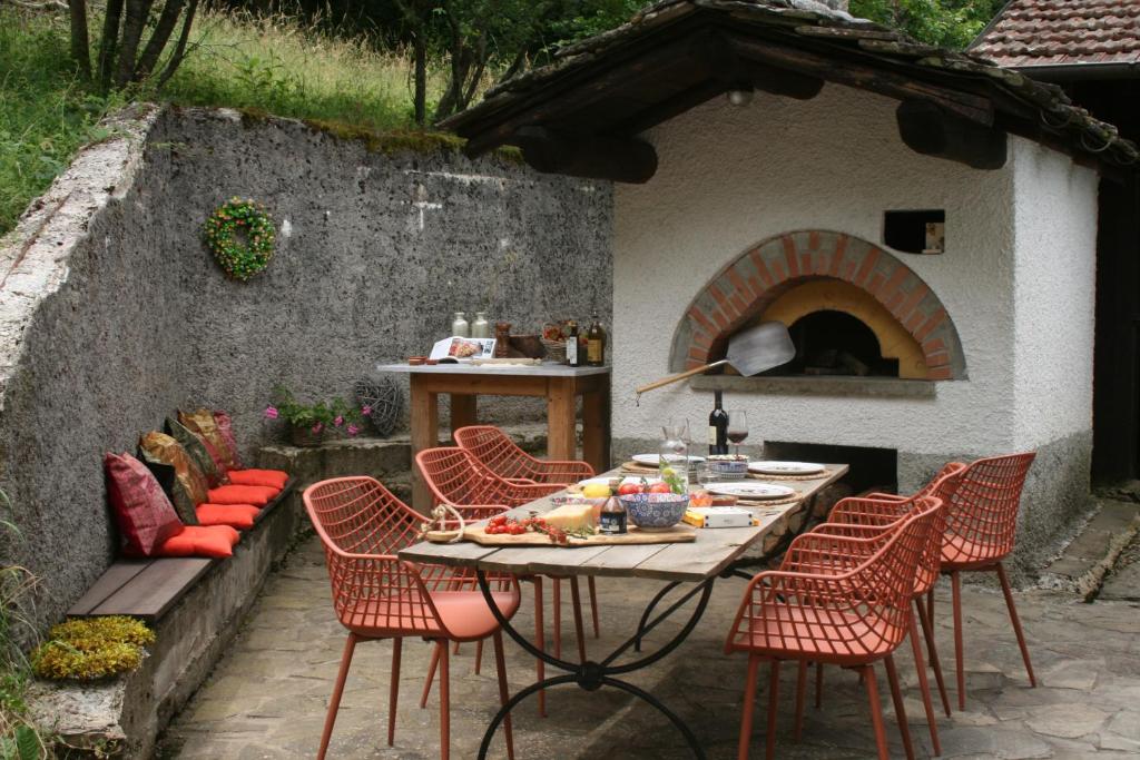 une table et des chaises devant un four à pizza dans l'établissement Casale delle farfalle, à Tornolo