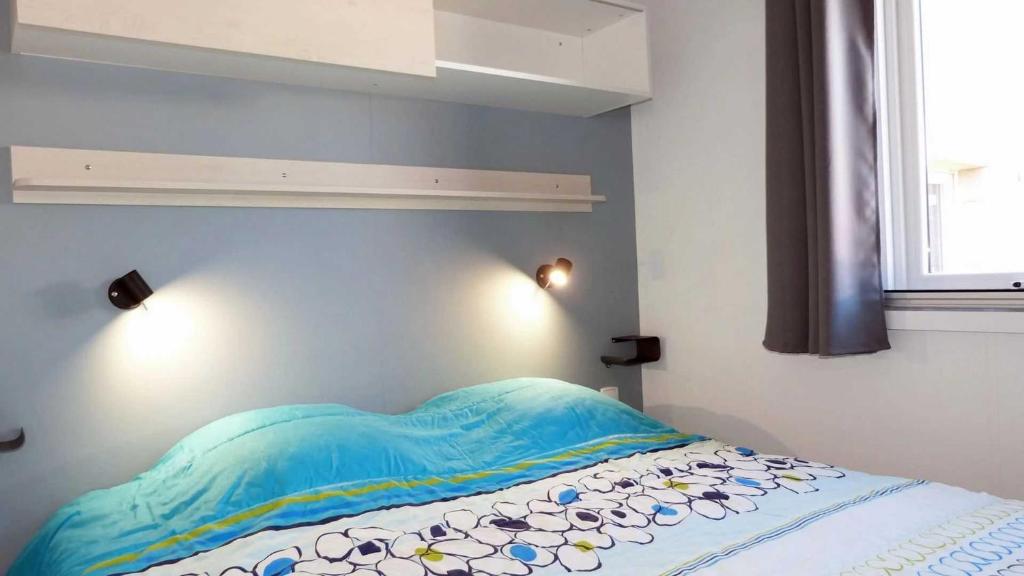 - une chambre avec un lit à tête bleue dans l'établissement Camping 4 étoiles - Parc aquatique - efacff, à Hyères