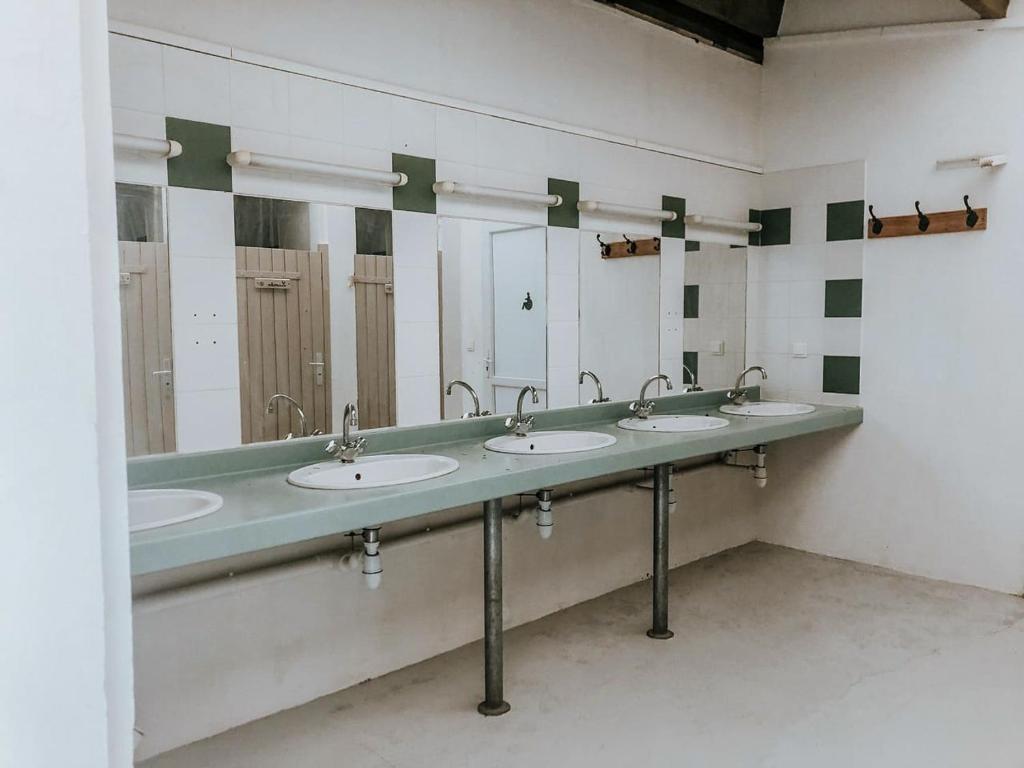 - une salle de bains commune avec 4 lavabos et miroirs dans l'établissement Lodg'ing Nature Camp Dordogne, à Lacave