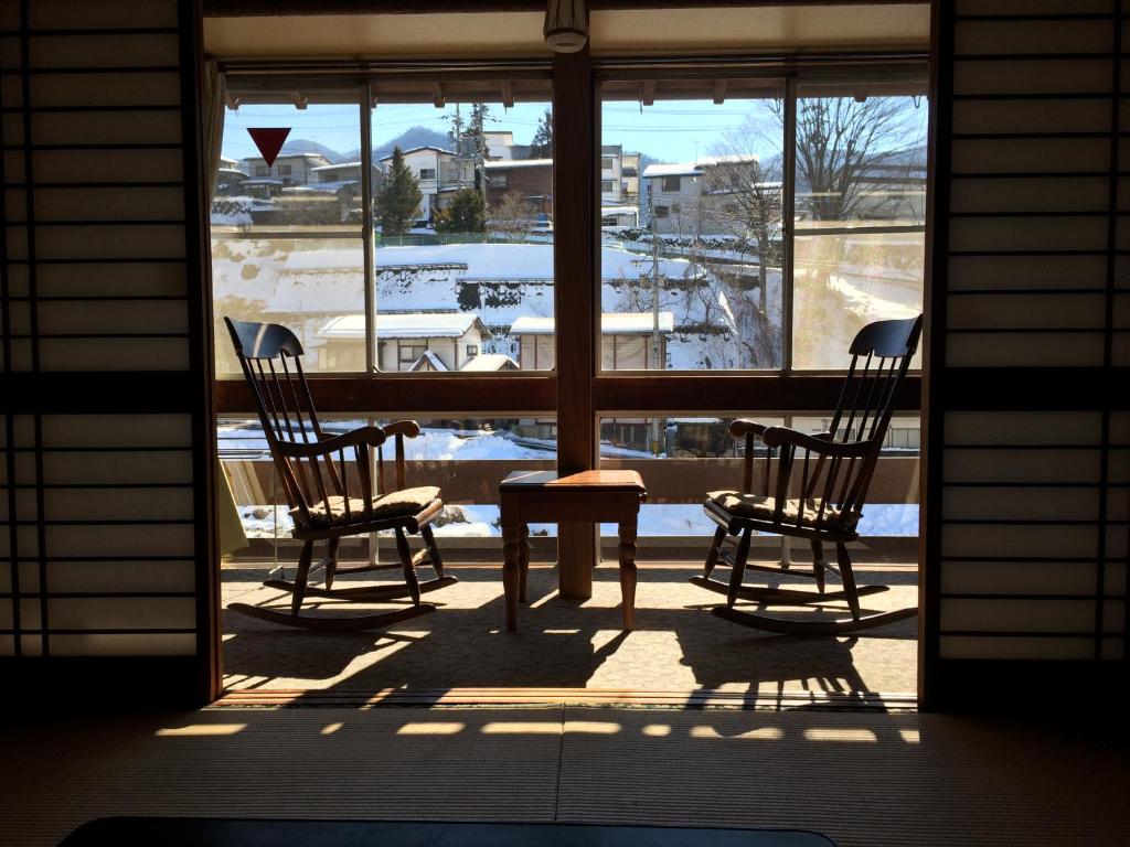 - une terrasse couverte avec 2 chaises et une table devant une fenêtre dans l'établissement Yudanaka Onsen Yamazakiya, à Yamanouchi