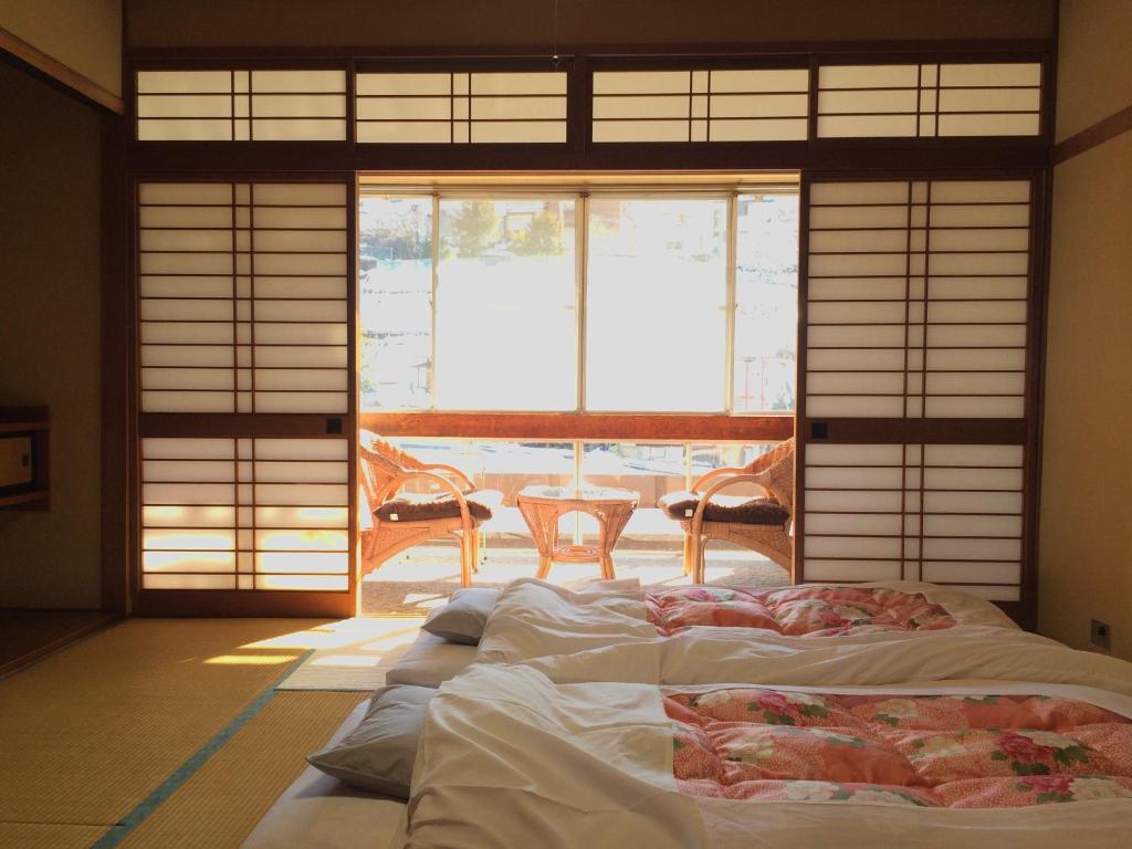 - une chambre avec un grand lit en face d'une fenêtre dans l'établissement Yudanaka Onsen Yamazakiya, à Yamanouchi