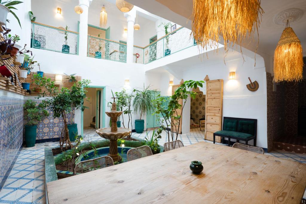 Cette grande chambre dispose d'une table en bois et de plantes. dans l'établissement Riad Lkhlil, à Marrakech