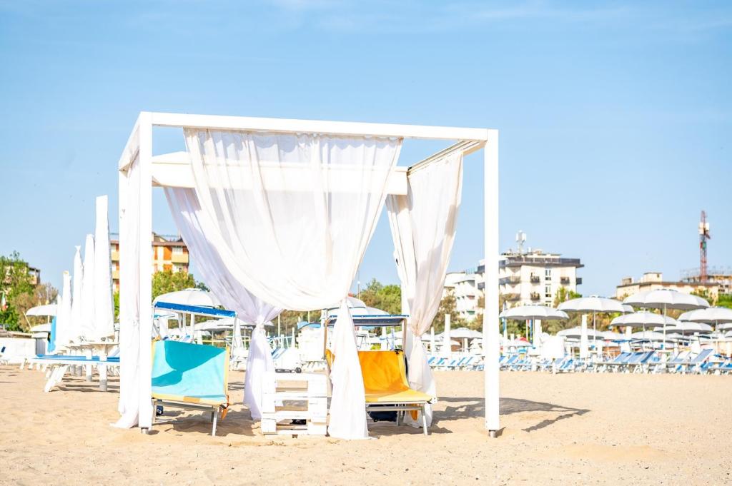 - un auvent sur une plage avec des chaises et des parasols dans l'établissement Hotel Mara, à Rimini