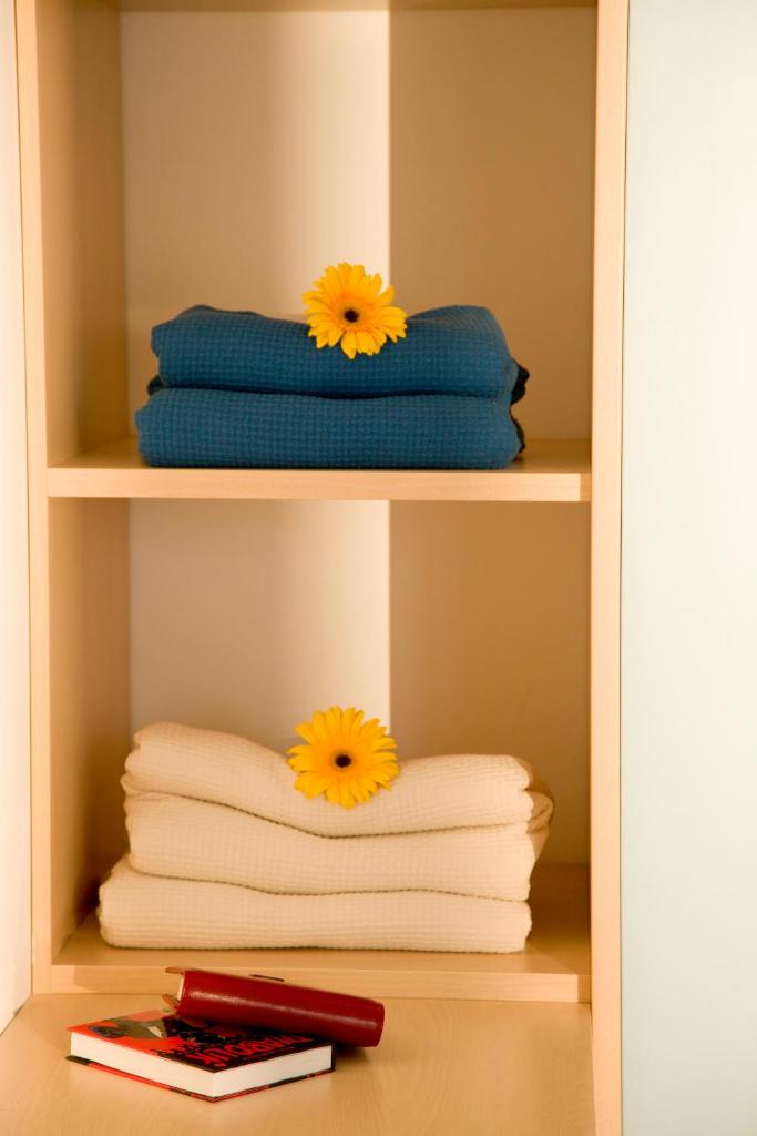 une étagère avec des serviettes et deux fleurs sur elles dans l'établissement Residence I Giardini Del Conero, à Porto Recanati