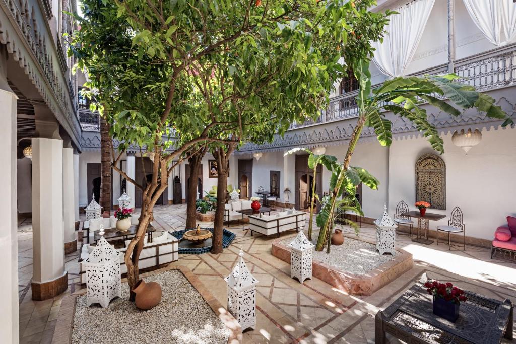 une cour avec des arbres et des bancs dans un bâtiment dans l'établissement Riad Les Jardins d'Henia, à Marrakech