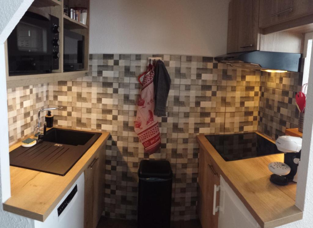 une cuisine avec un évier et un comptoir recouvert de carrelage. dans l'établissement Superbe appartement en résidence skis aux pieds, à Courchevel