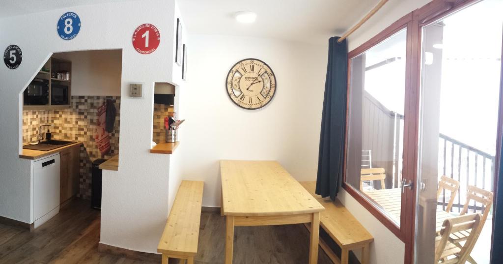 une cuisine avec une table et une horloge au mur dans l'établissement Superbe appartement en résidence skis aux pieds, à Courchevel