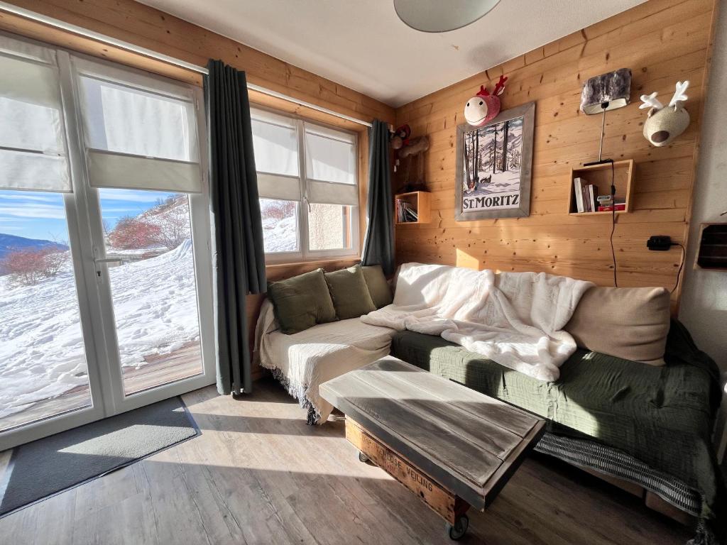 un salon avec un canapé et une grande fenêtre dans l'établissement Terrasse, vue imprenable et accès direct pleine nature, votre refuge idéal, à Orcières