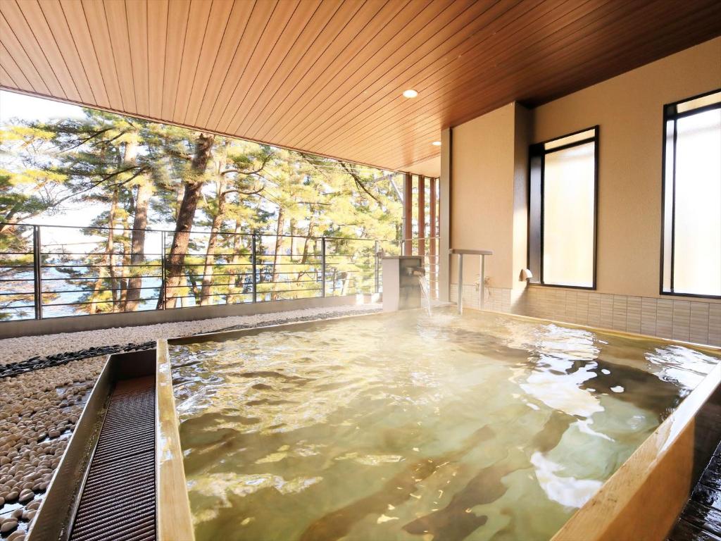 - une grande piscine d'eau dans une chambre avec fenêtres dans l'établissement Hamabeno Ryouriyado Houraikan, à Kamaishi