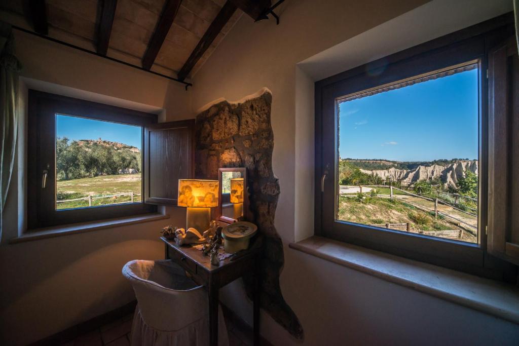 une chambre avec deux fenêtres et une table avec une lampe dans l'établissement Villa I Calanchi Di Civita, à Bagnoregio