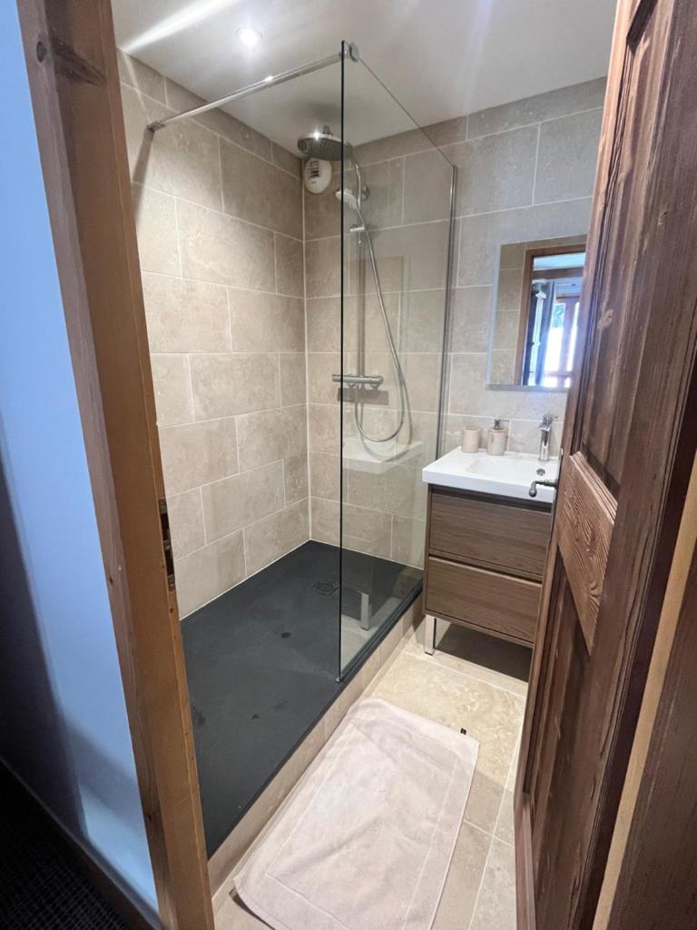 une salle de bain avec une douche en verre avec un lavabo dans l'établissement Arc 1950 Appartement 4 personnes Ski aux pieds, à Arc 1950