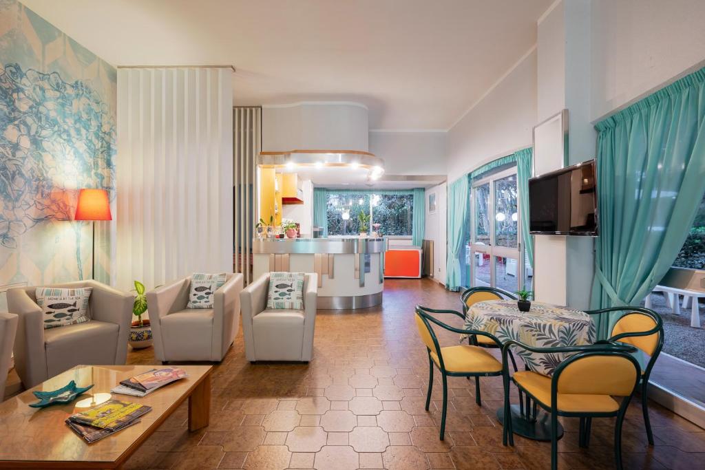 un salon avec une table et des chaises et une cuisine dans l'établissement Hotel Parco dei Pini - 100mt dal Mare, à Follonica