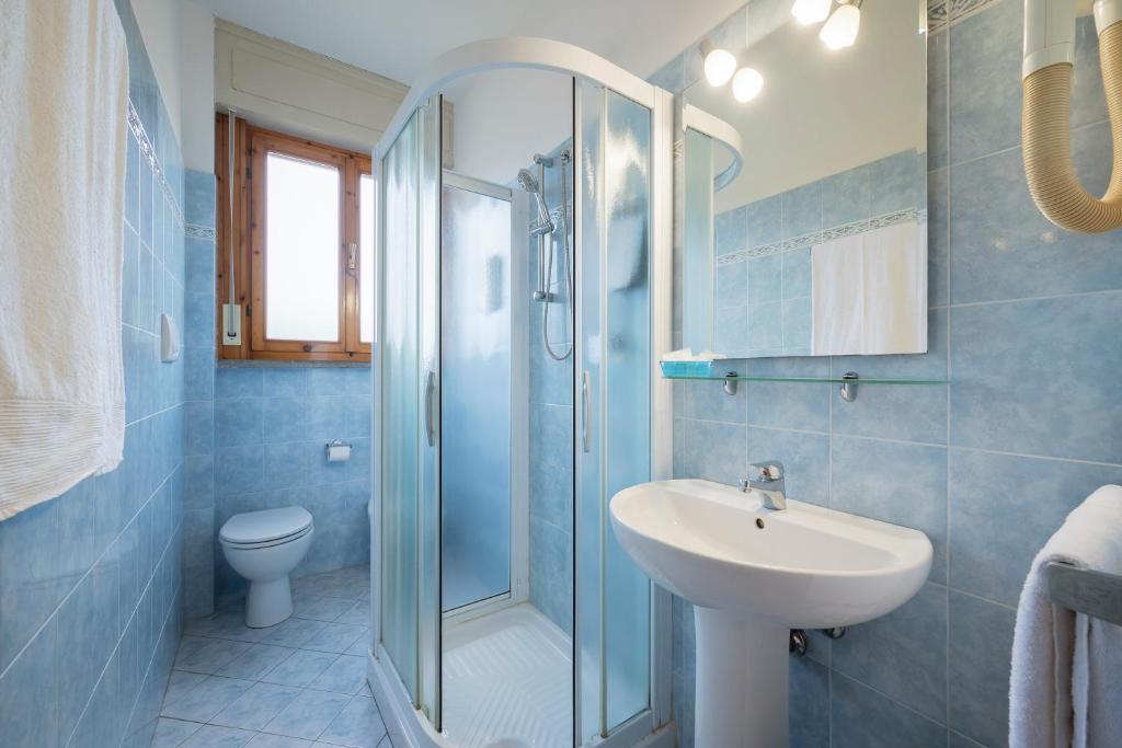 une salle de bain bleue avec un lavabo et une douche dans l'établissement Hotel Parco dei Pini - 100mt dal Mare, à Follonica 76 autres photos