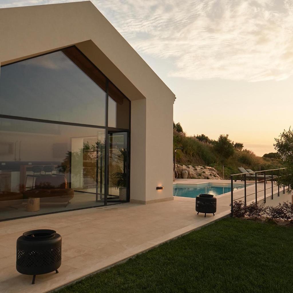 une maison avec une grande porte en verre et une piscine dans l'établissement JATU Retreat, à San Costantino