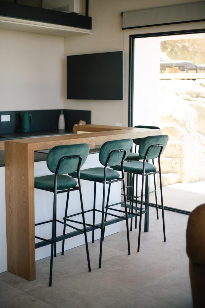- un bar avec quatre tabourets de bar verts dans une pièce dans l'établissement JATU Retreat, à San Costantino