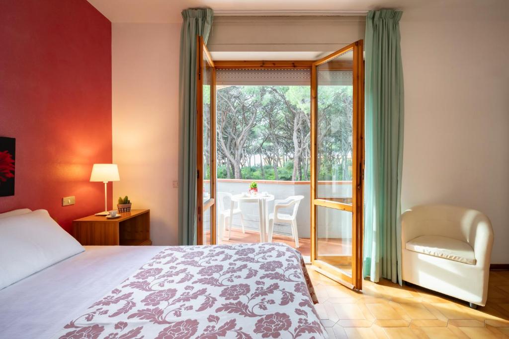 une chambre avec un lit et un balcon avec une table dans l'établissement Hotel Parco dei Pini - 100mt dal Mare, à Follonica