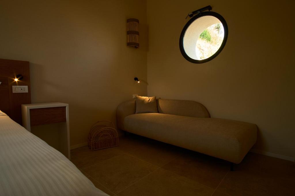 une chambre avec un canapé et une fenêtre ronde dans l'établissement JATU Retreat, à San Costantino 70 autres photos