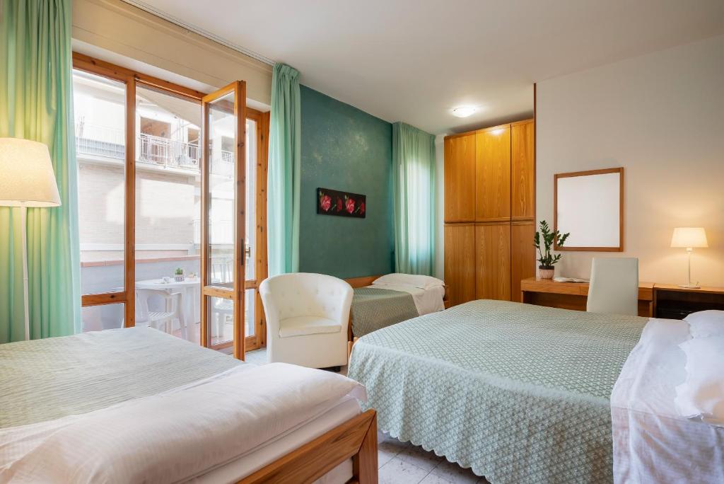 une chambre d'hôtel avec deux lits, une table et des chaises dans l'établissement Hotel Parco dei Pini - 100mt dal Mare, à Follonica