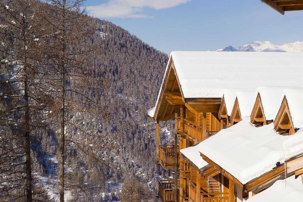 un bâtiment recouvert de neige avec des montagnes en arrière-plan dans l'établissement CENTRE STATION 1800 - Dernier étage Rénové - 2 Chambres 6 personnes - Skis aux pieds, aux Orres