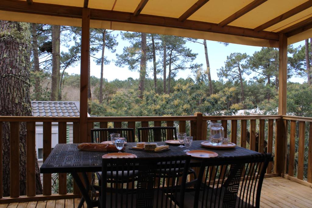 - une table sur une terrasse couverte avec une moustiquaire et une table et des chaises dans l'établissement Mobilhome Les Embruns by Siblu, à Lège-Cap-Ferret 11 autres photos