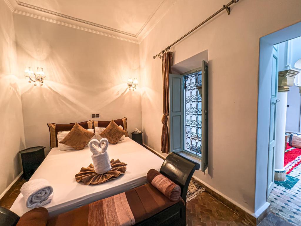 une chambre avec un lit avec une chaise et une fenêtre dans l'établissement Riad L'Orchidée Suites & Spa, à Marrakech