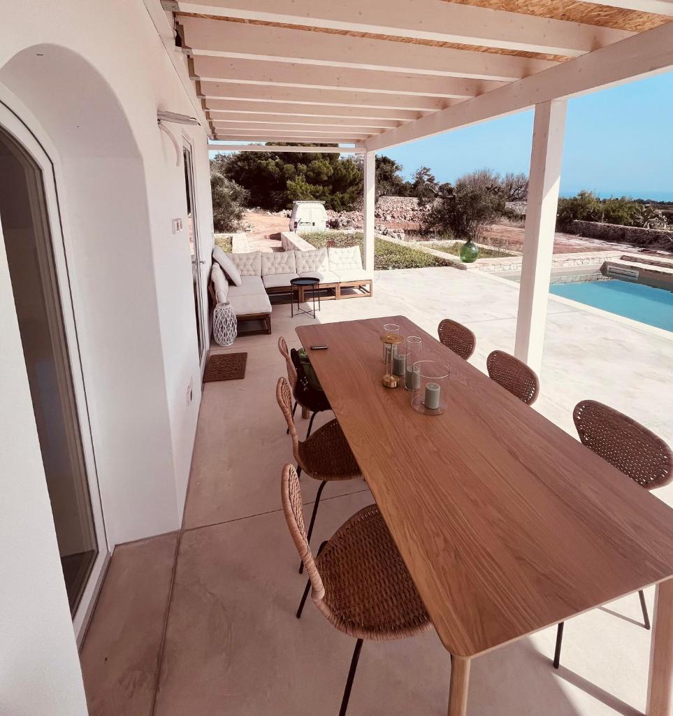 une table et des chaises en bois sur une terrasse avec une piscine dans l'établissement Dimora Vereto, à Morciano di Leuca